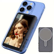 Wireless selfie monitor attached to a blue smartphone showing a woman's live rear camera preview with magnetic mount accessory.